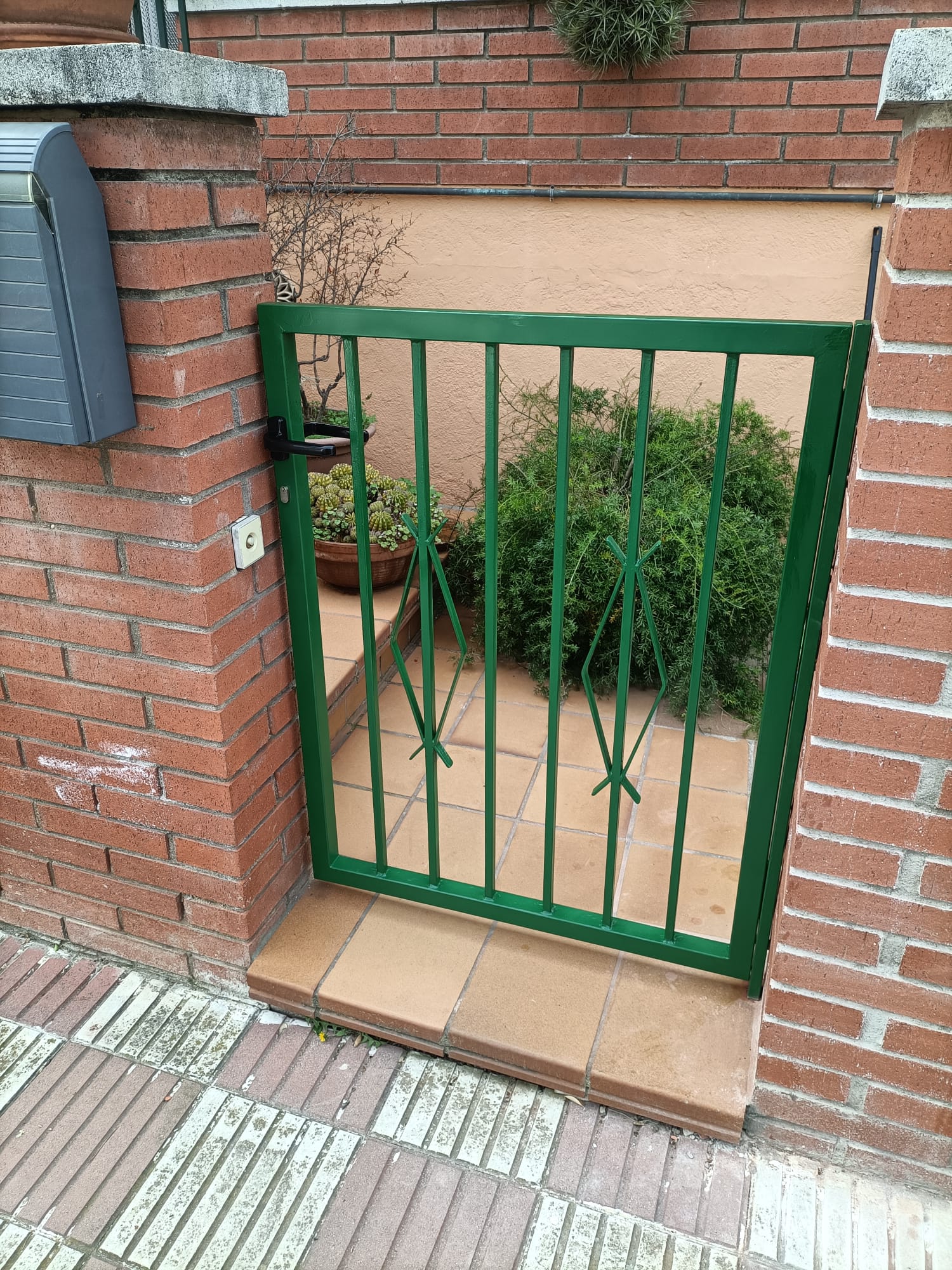 Cancela metálica verde con barrotes para entrada de jardín