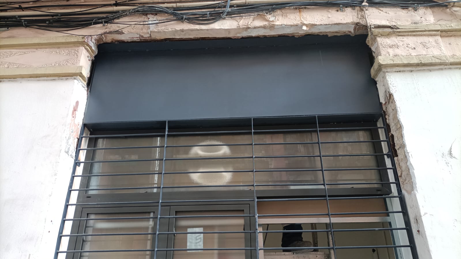 Cierre metálico enrollable con reja de seguridad en local